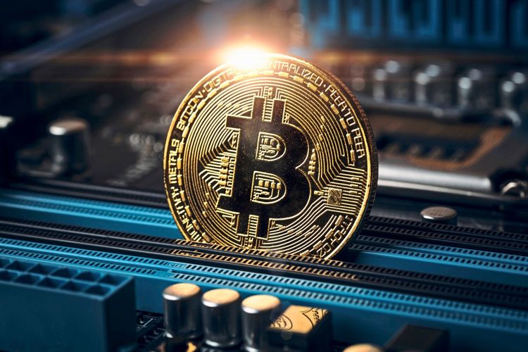 Goldene Bitcoin-Münze auf einer Computerplatine, symbolisierend Kryptowährung und Technologie