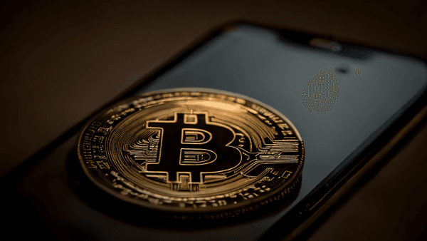 Eine Bitcoin-Münze auf einem Smartphone symbolisiert das einfache Versteuern von Krypto-Gewinnen