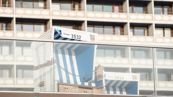 A beach chair in front of a building with many balconies