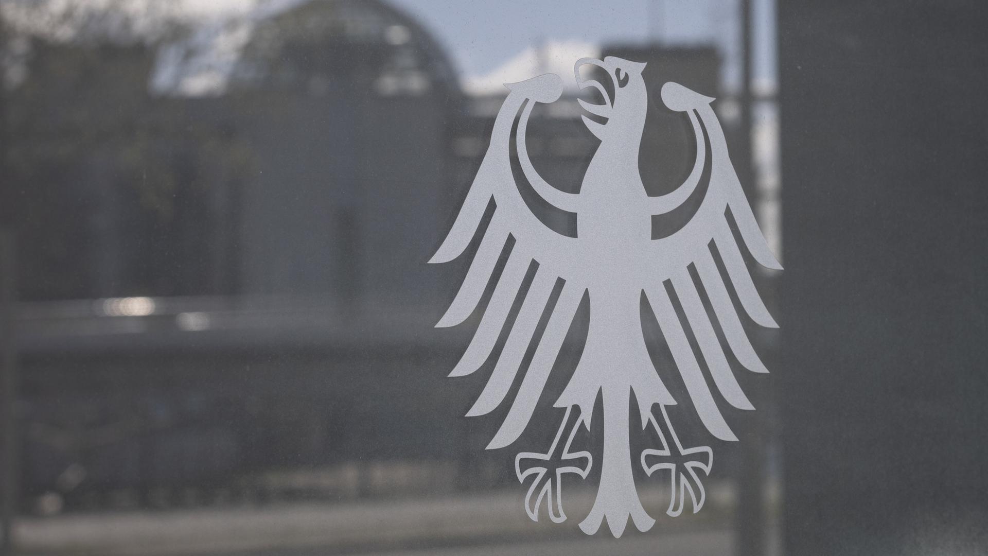 Der Bundesadler klebt an der Scheibe eines Ministeriums in der Spiegelung des Gl