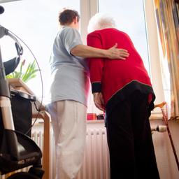 Eine Seniorin und eine Pflegerin schauen zusammen aus einem Fenster im Wohbereich eines Pflegeheims.