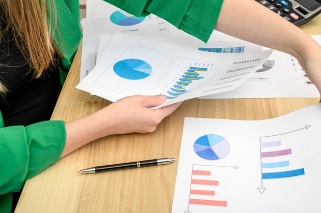 A woman sits at a desk at work and shuffles paper documents