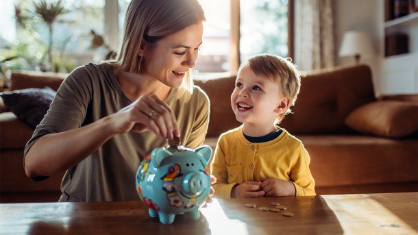 Mutter mit Kind neben einem Sparschwein