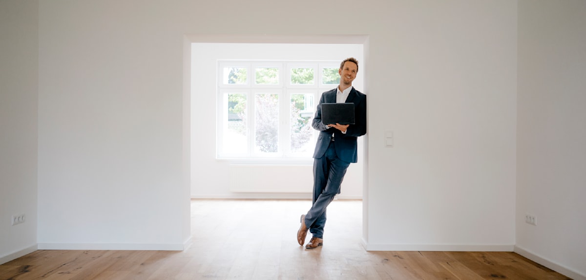 Estate agent waiting in newly refurbished home holding laptop