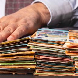 Eine Hand liegt auf Stapeln mit Euro-Geldscheinen