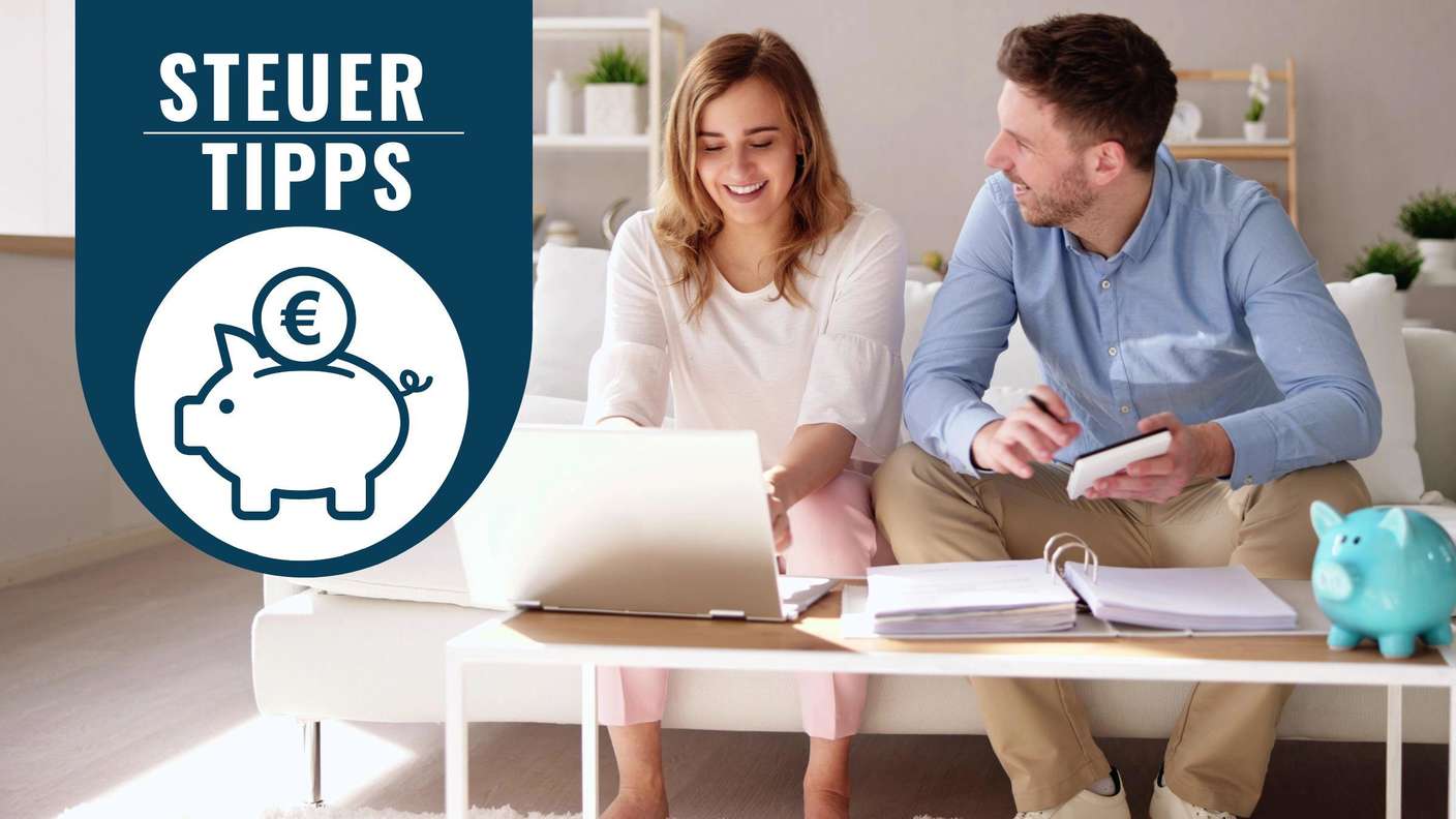 Ein Paar sitzt gemeinsam vor einem Laptop auf der Couch und schaut Unterlagen durch