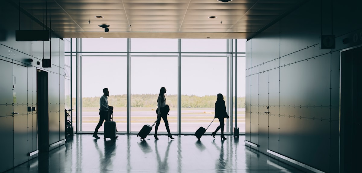 Side view of silhouette business colleagues pulling luggage while walking in corridor