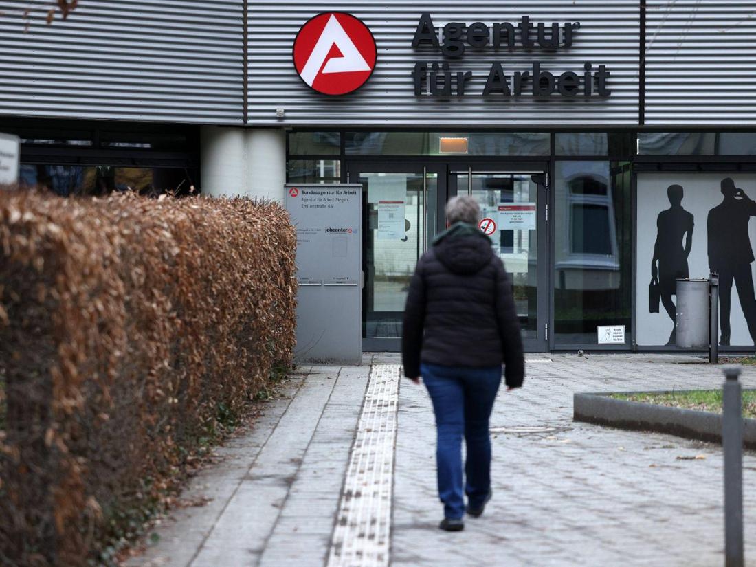 Eine Person läuft den Eingang einer Agentur für Arbeit zu.