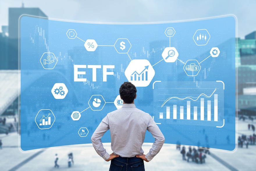 A person looking at a screen with the word ETF on it along with several investing diagrams