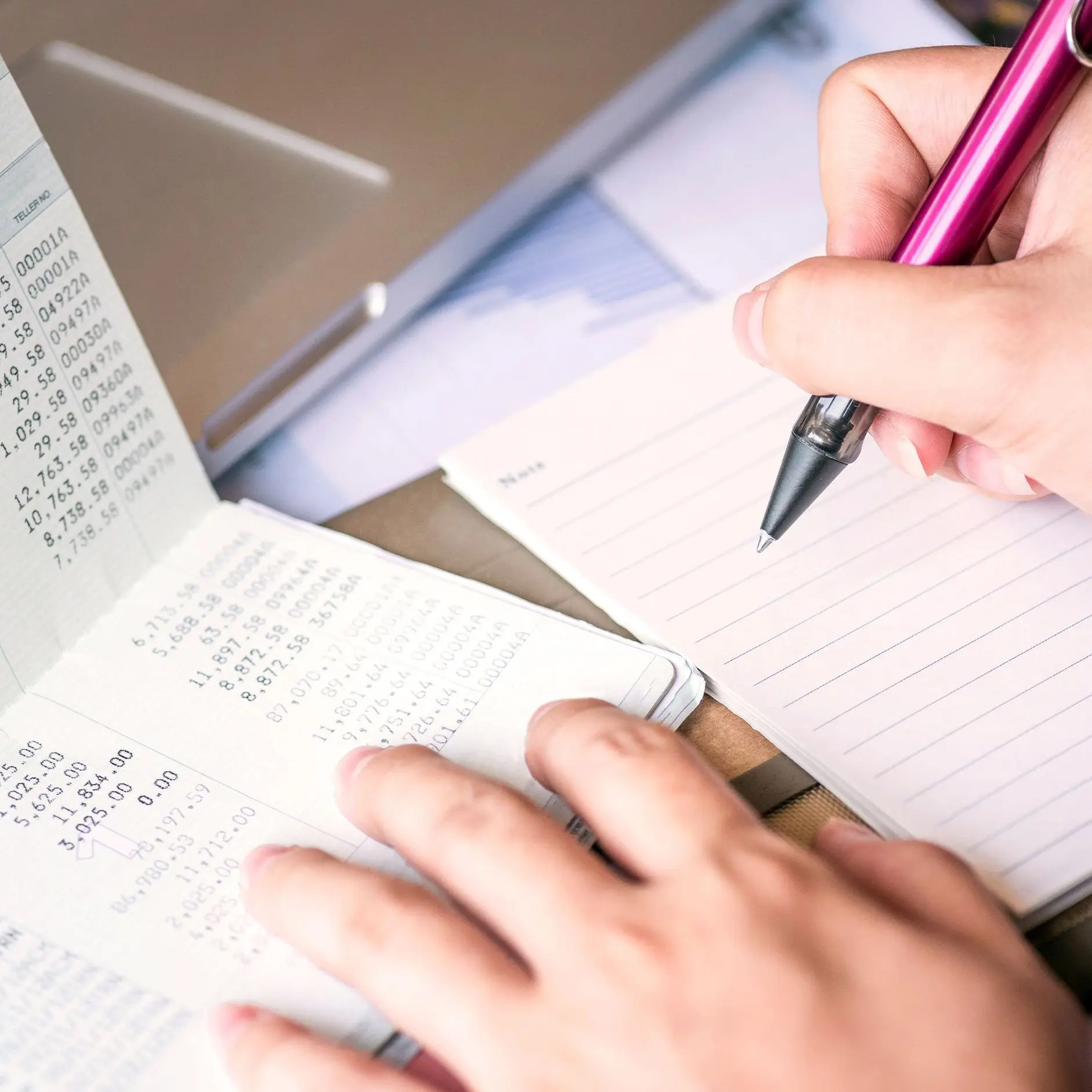 Hand writing in savings book symbolizing personal financial planning and emergency fund building